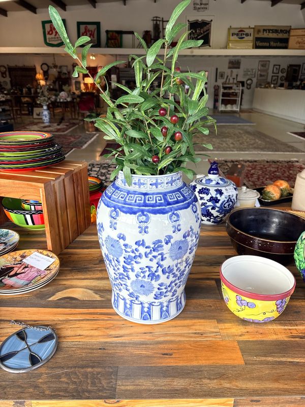 A blue and white porcelain vase filled with greenery