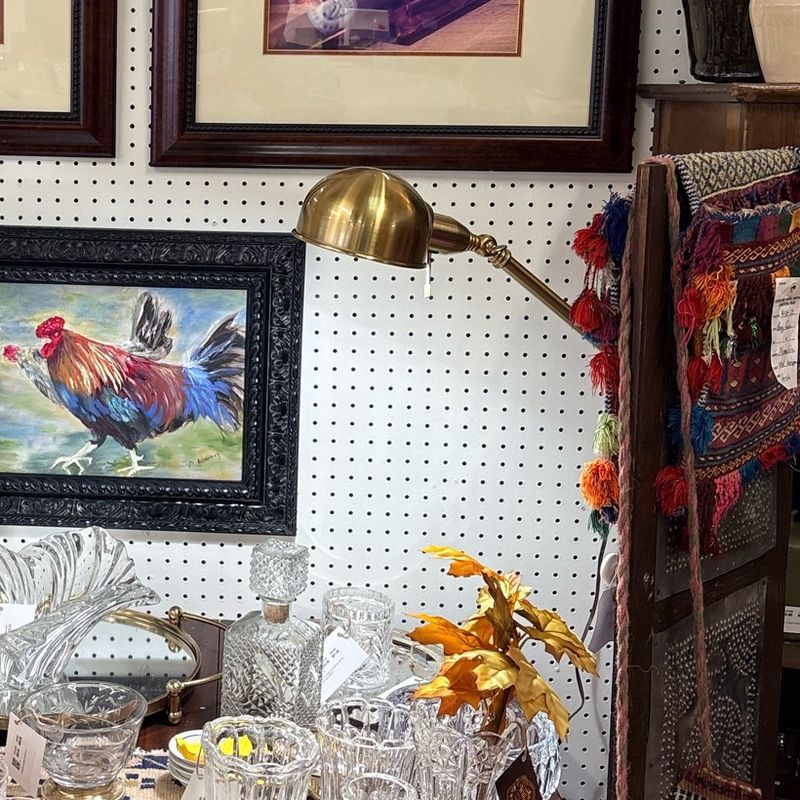 A brass lamp above a table of cut crystal and framed art