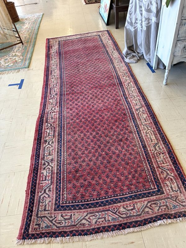 A red Persian runner with a small repeating pattern and ivory border